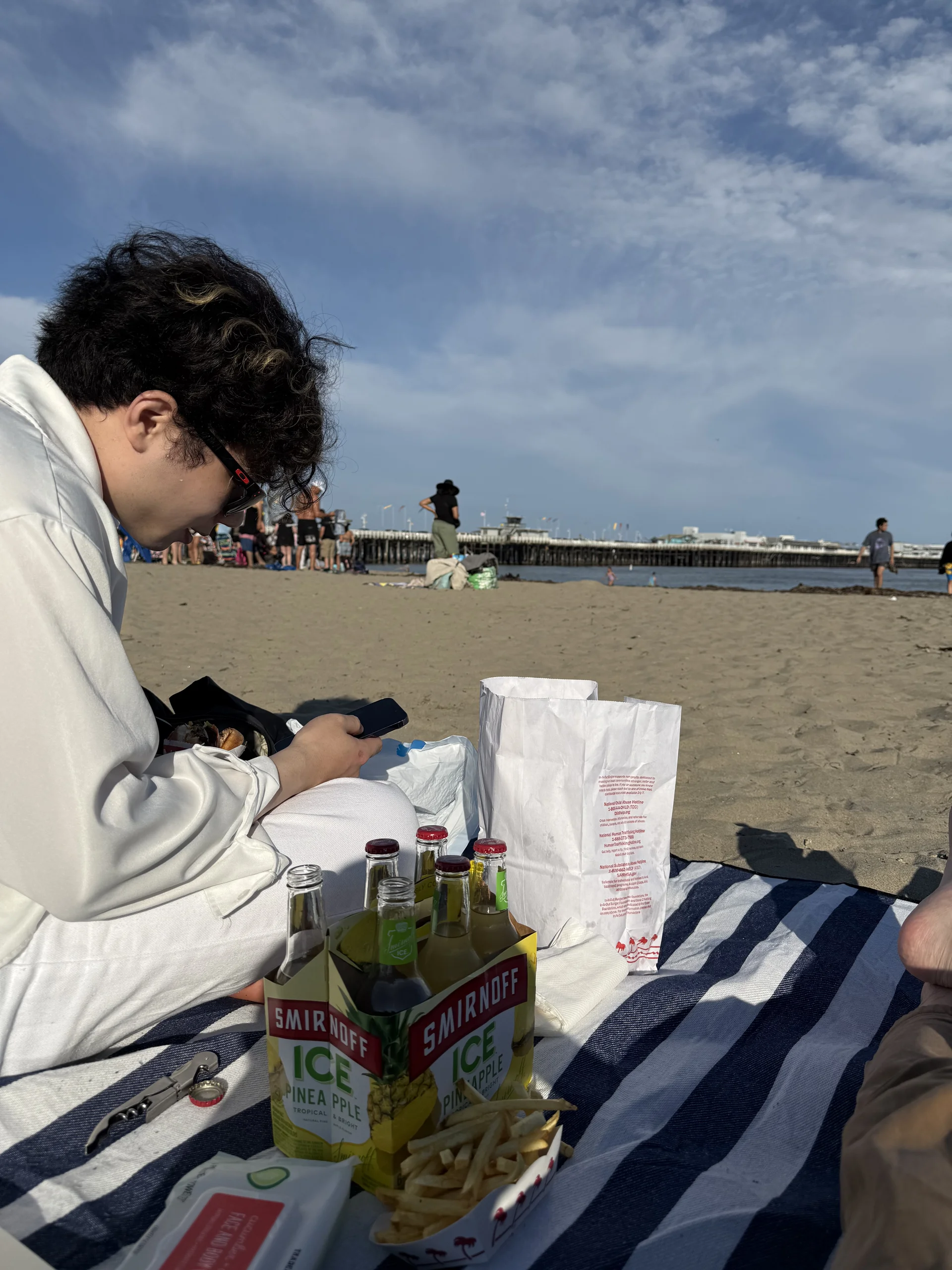 海灘野餐，桌布上有 Smirnoff 飲料與薯條