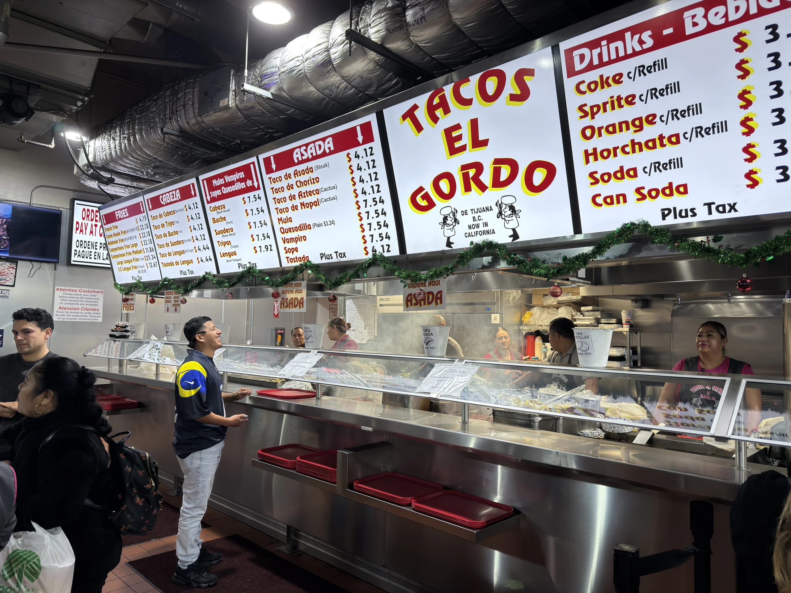 Tacos El Gordo 點餐櫃檯,牆上掛著大型菜單與價格