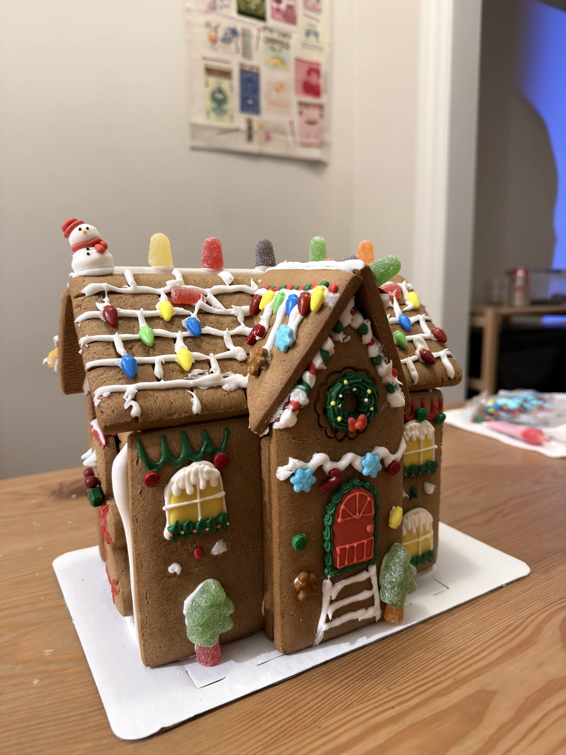 桌上擺放完成的薑餅屋,屋頂與牆面以糖霜與彩色糖果裝飾