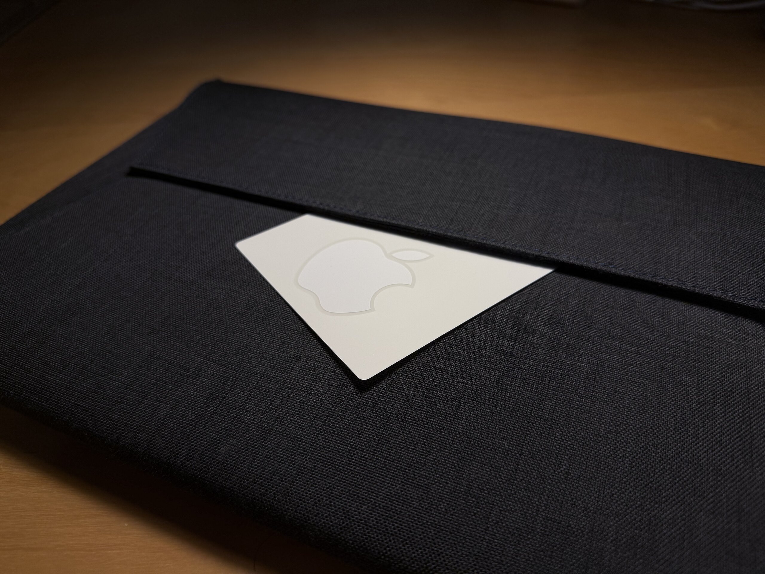 一個黑色的布製電腦保護套中夾著一張白色的 Apple logo 貼紙