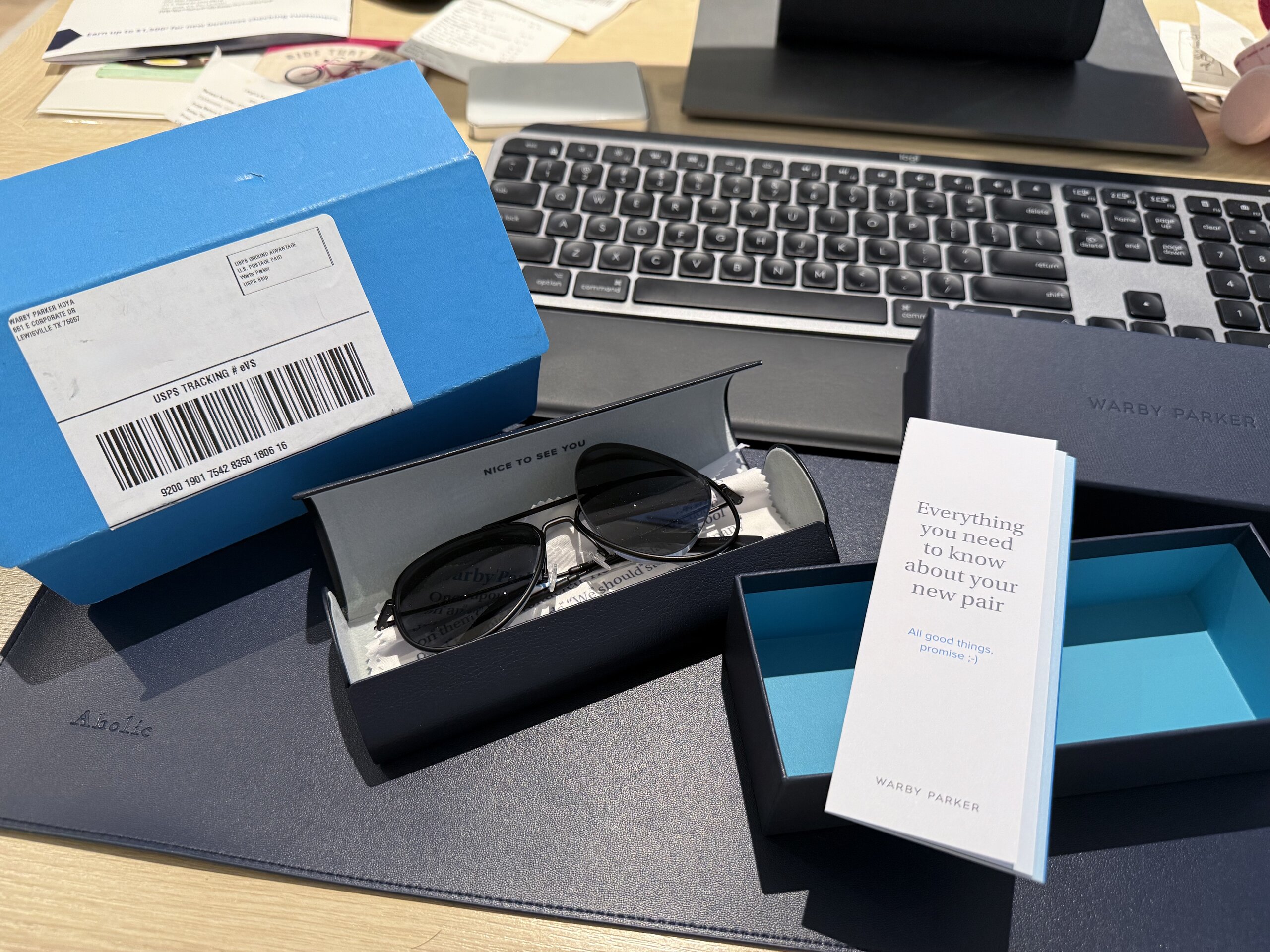Warby Parker Raider 墨鏡與藍色包裝盒及產品說明書擺放在桌上